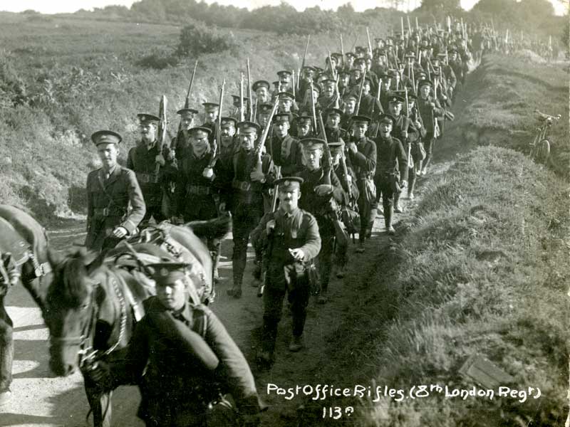 There are hundreds of men marching in rows as far back as the photograph spans. They all carry rifles and wear army uniforms. The image is black and white. 