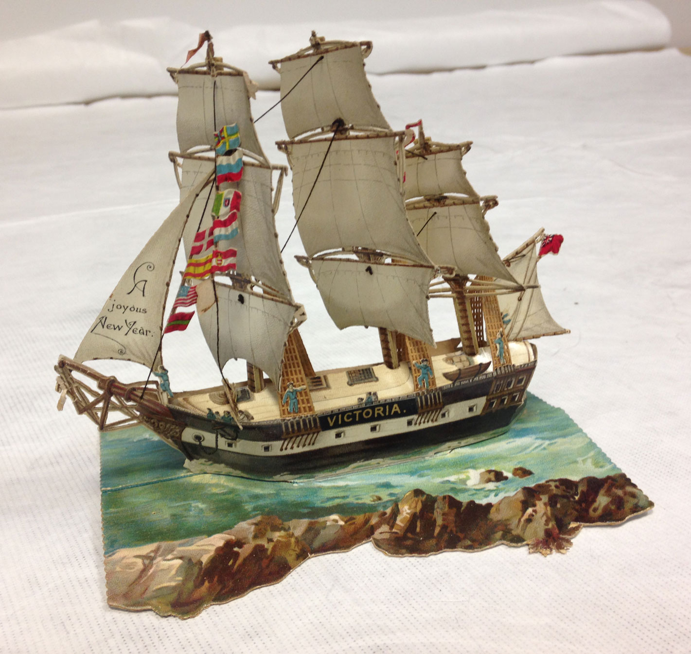 Pop-up New Year card of a galleon ship called 'Victoria' on the sea.