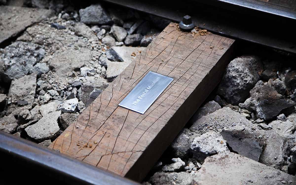 An engraved steel plaque on a wooden sleeper at Mail Rail. It reads The Postal Museum