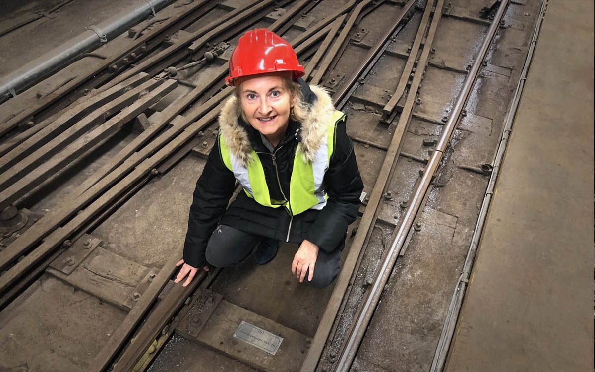 Photograph of a Mail Rail sleeper sponsor viewing an engraved plaque on the tracks.