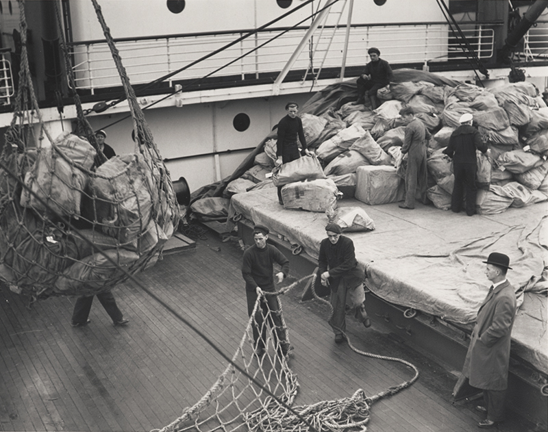 A black and white photograph showing crew unloading mail from a ship