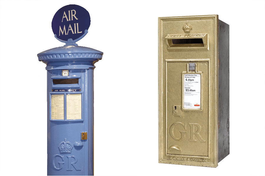 A blue pillar box for letters with the words 'Air Mail' fixed to a sign on the top of the box. To the right is a small rectangular post box, painted in gold.
