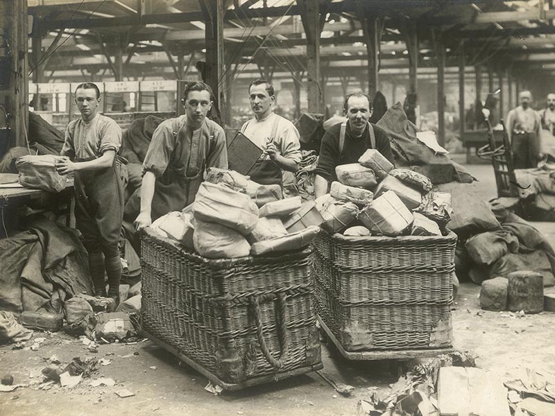 A group of men with wicket baskets carrying letters.