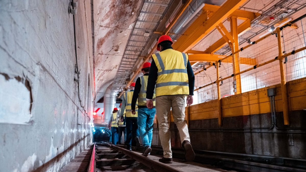 We can see the tour attendees descending down the Mail Rail tunnel, wearing their protective gear.