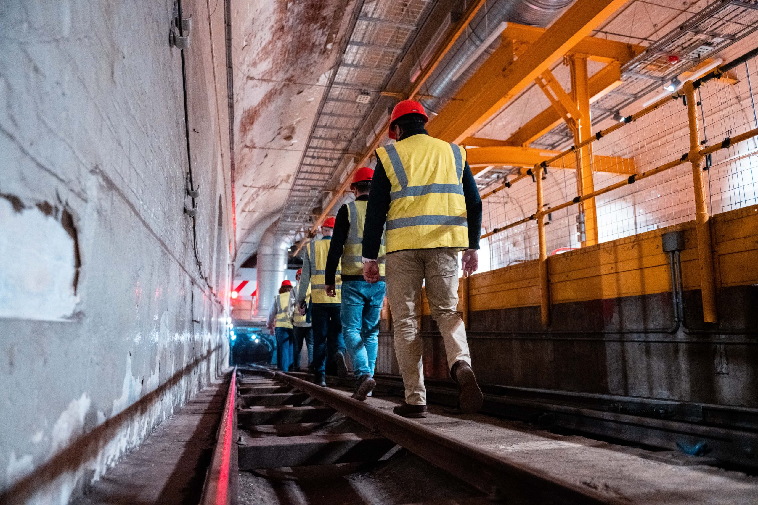 We can see the tour attendees descending down the Mail Rail tunnel, wearing their protective gear.