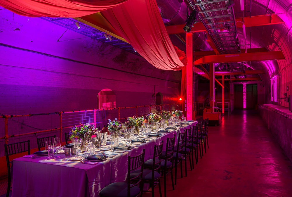 An event table set up in the Mail Rail venue space with purple lighting and decor.