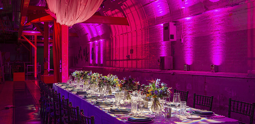 An event table set up in the Mail Rail venue space with purple lighting and decor.
