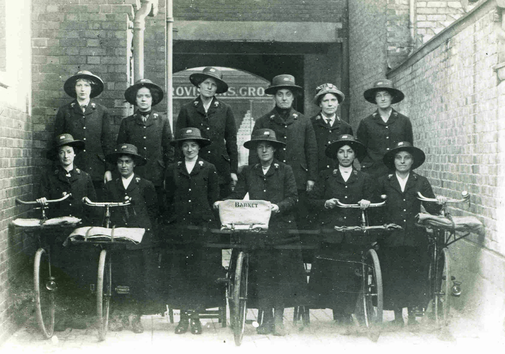 Black and white photograph of Barnet postwomen standing next to bicycles. 