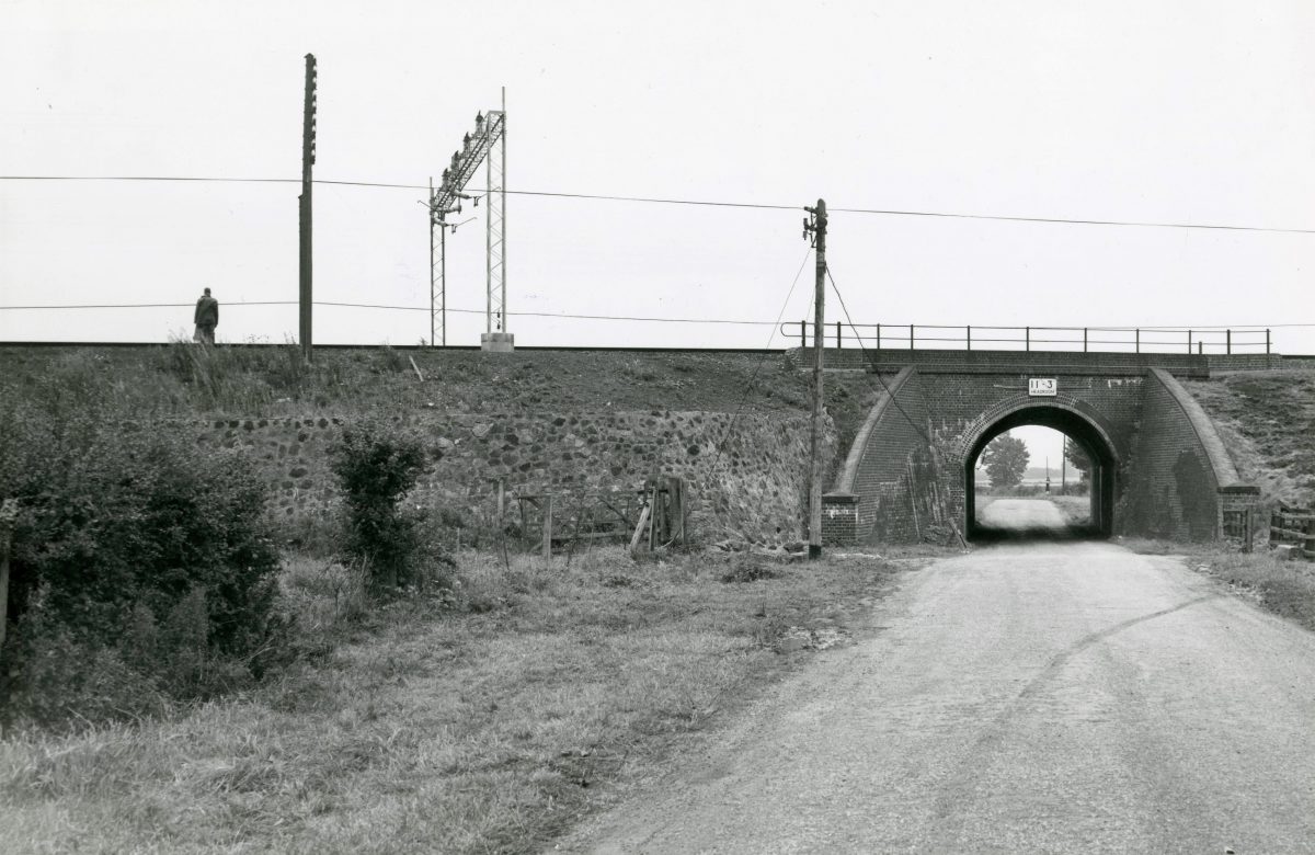 Black and white photograph of a railway line going over a road.