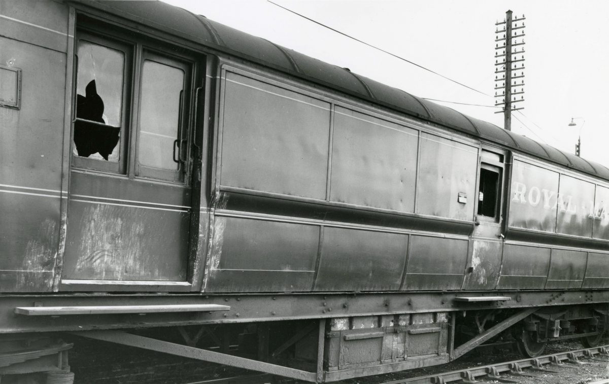 Black and white photograph of a Royal Mail train carriage with smashed windows.