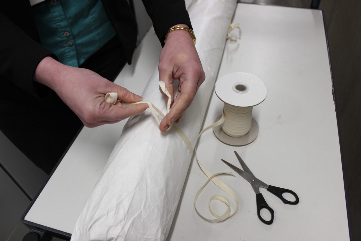 Rolled documents secured in two places with white cotton tape