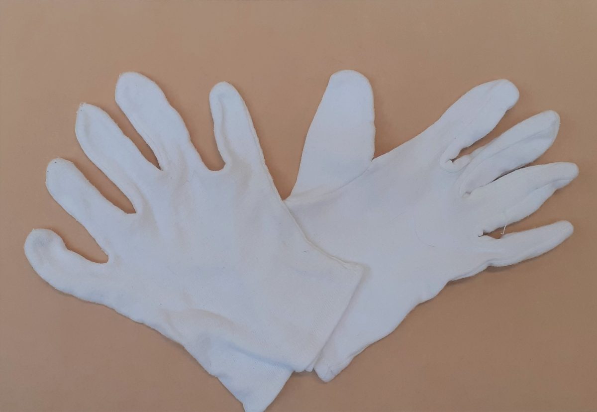 One pair of small white cotton gloves. The gloves overlap slightly