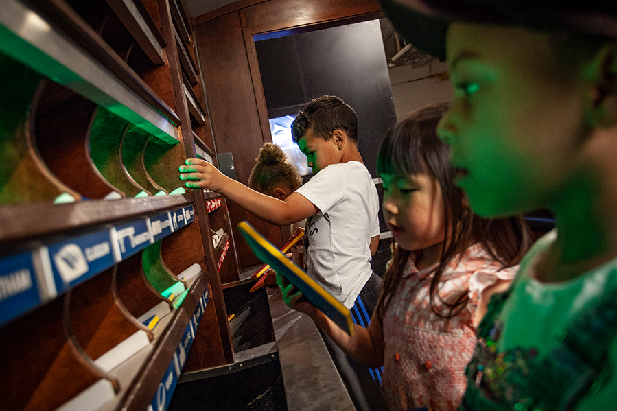 Two boys and two girls play with an interactive exhibition. They are holding red and blue wooden boards and focusing on their activity.