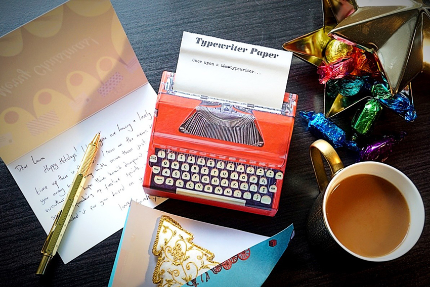 Photo showing a box with typewriter paper and other stationery on a desk.