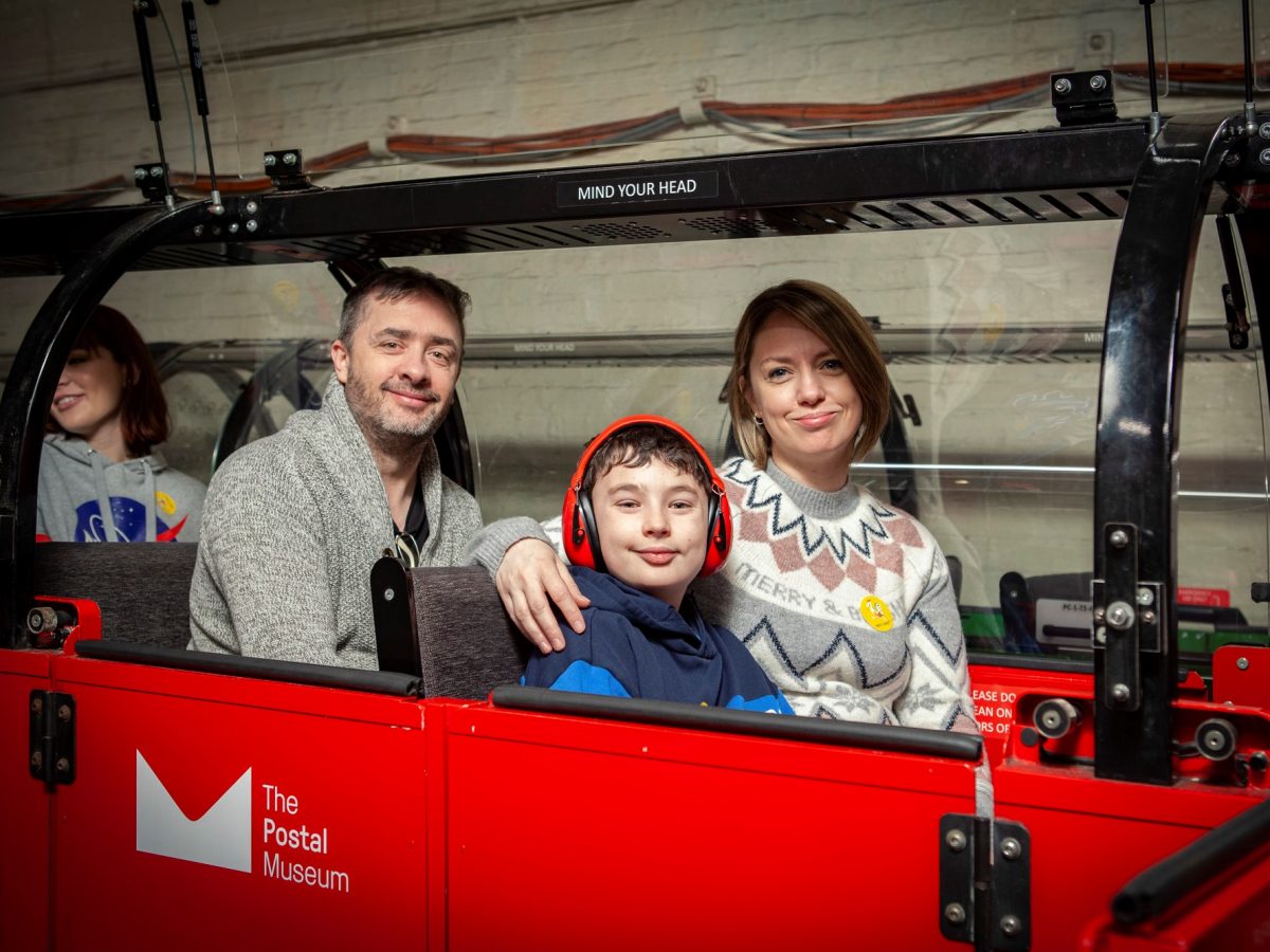 Photo of a family riding the red miniature Mail Rail train.