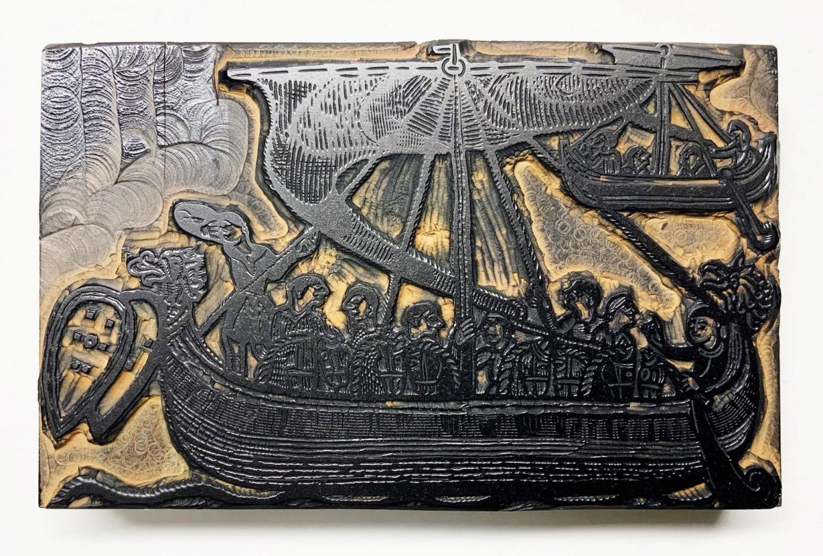 Carved piece of wood featuring a design of men in a ship.