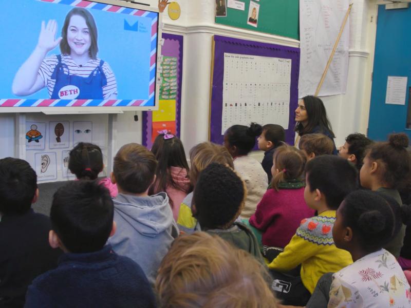 The Jolly Postman virtual session - photo showing children in a classroom watching the session on a screen.