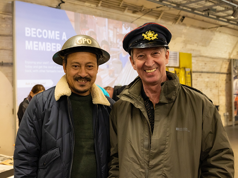 Two Postal Workers are smiling while playing dress up