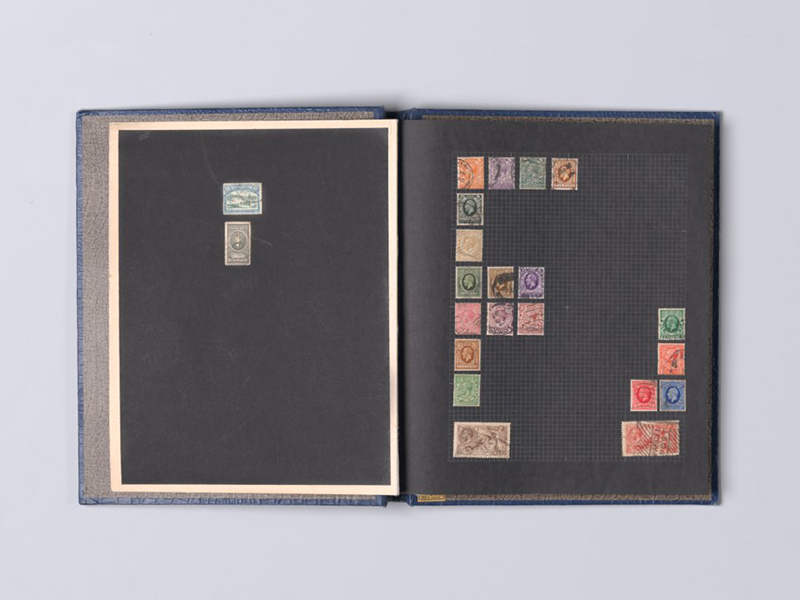 A photo of a stamp album, open to show a page with different coloured stamps arranged in the shape of the letter 'F'.