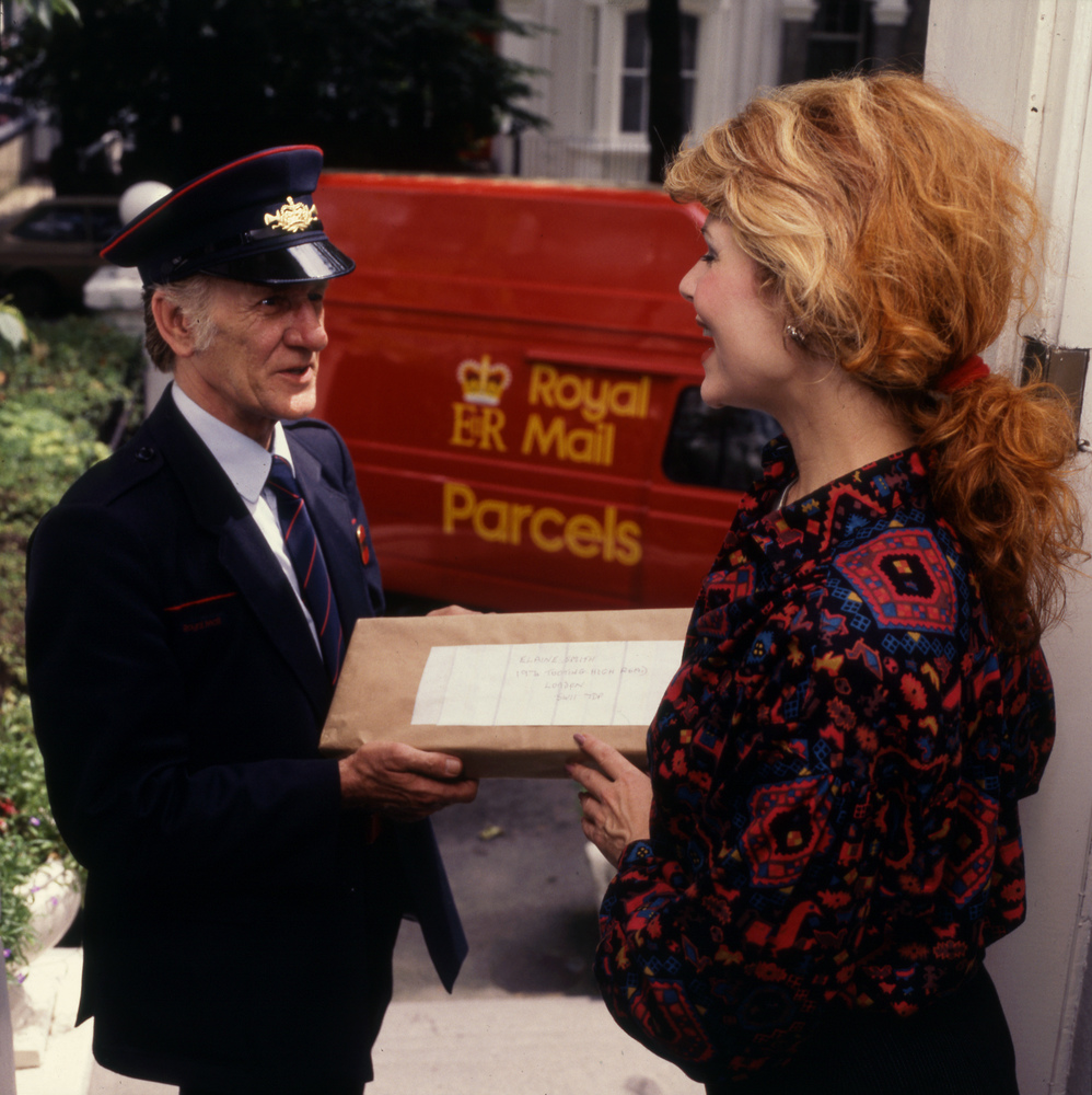 A postman delivers mail to a woman in Hammersmith Grove, London, 1987.