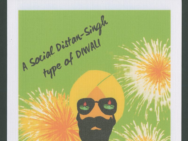 Diwali card designed by The Card Wala Co. On the front of the card is printed 'A Social Distan-Singh / type of DIWALI'. The front of the card features a green background, against which three illustrated yellow and orange fireworks are exploding. In the bottom centre of the design is an illustrated face of an Asian man with a beard wearing a yellow turban. He is wearing sunglasses, in which are reflected two small oil lamps.
