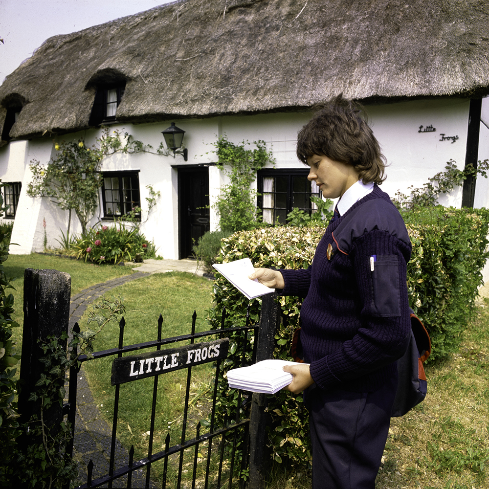 Colour photo showing delivery of mail by van by postwoman