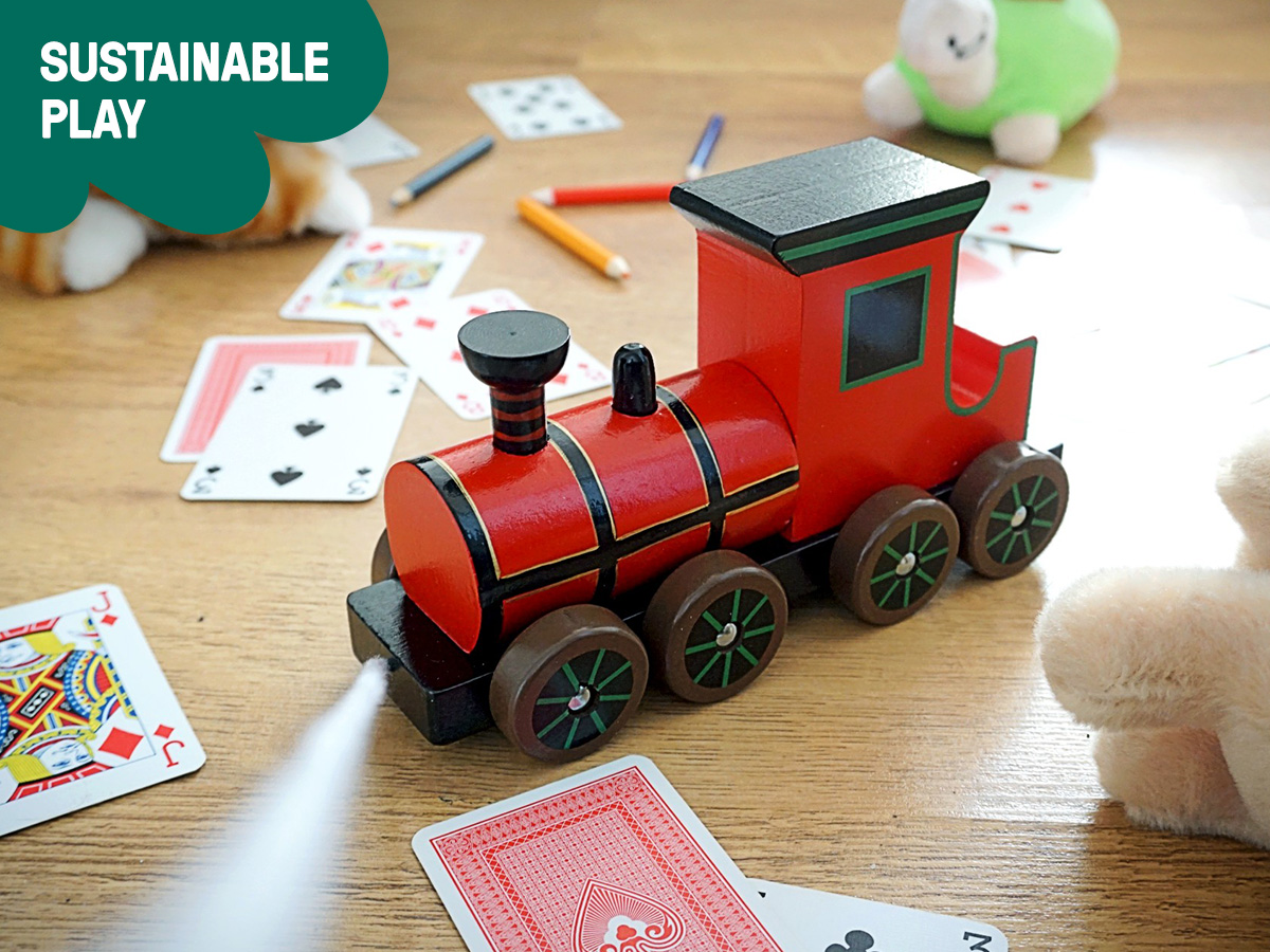 Photograph of a red wooden toy train on the floor. Banner text saying 'Sustainable play'.