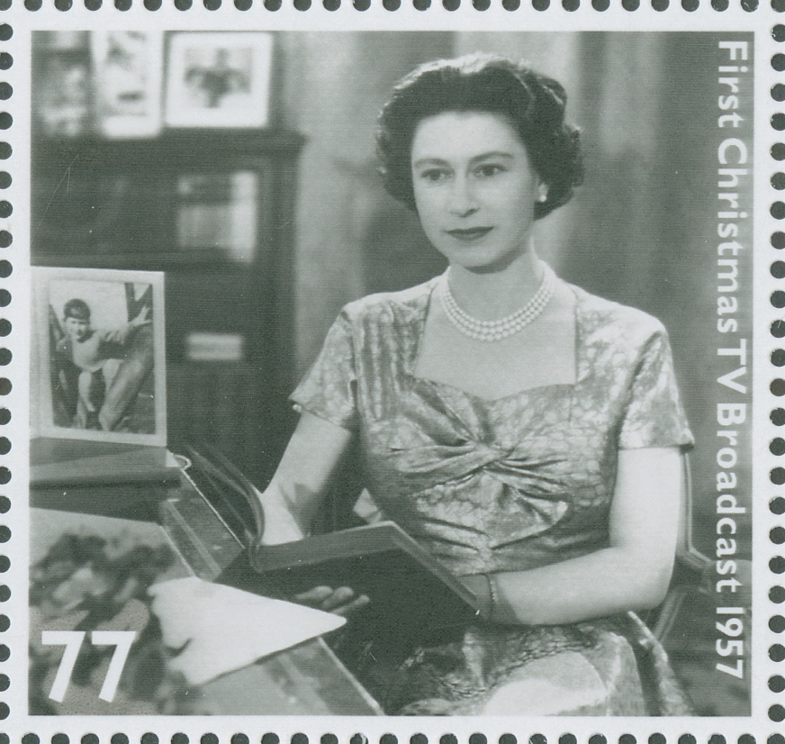 A scan of a stamp showing a black and white photograph of Queen Elizabeth II, reading from a book in her first Christmas TV broadcast in 1957.