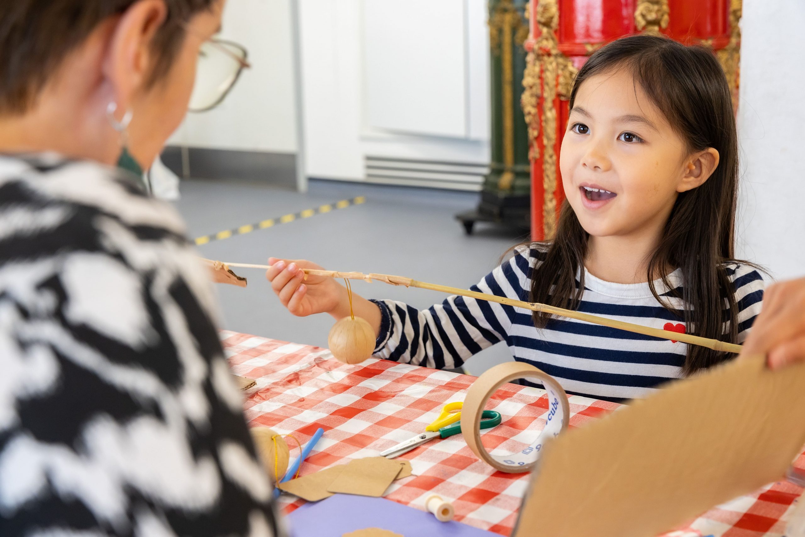 A child is using masking tape to attach two straws together as she crafts and builds.