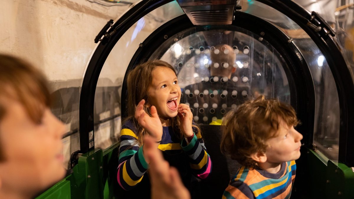 Happy children sat in a Mail Rail carriage.