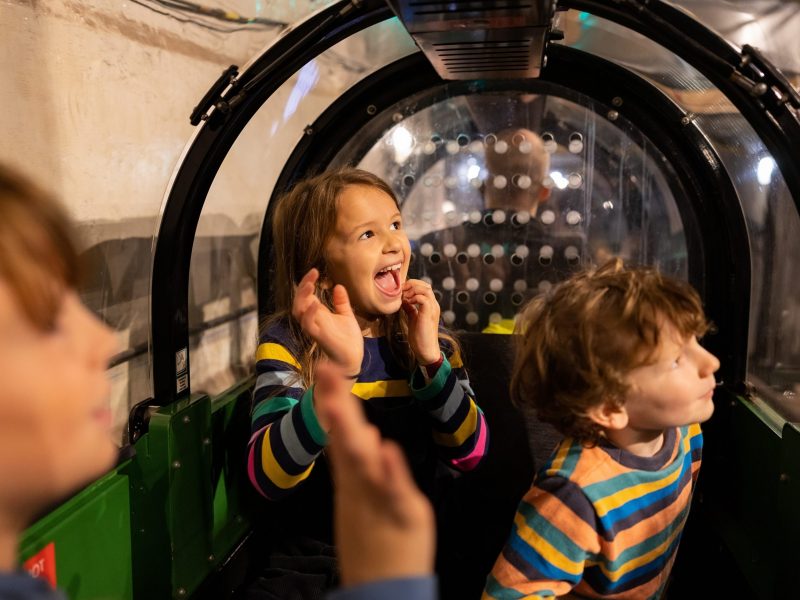 Happy children sat in a Mail Rail carriage.