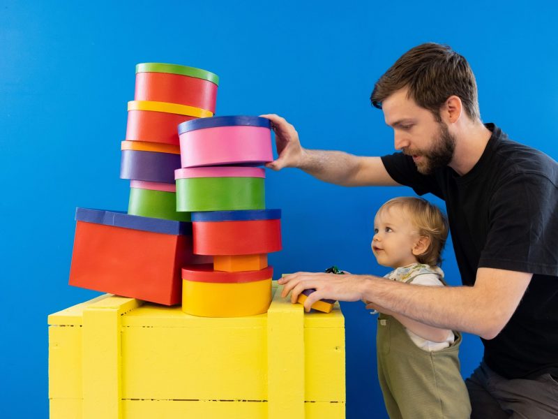 Father helps his young son stack multi-coloured building blocks as part of the Post and Play activities
