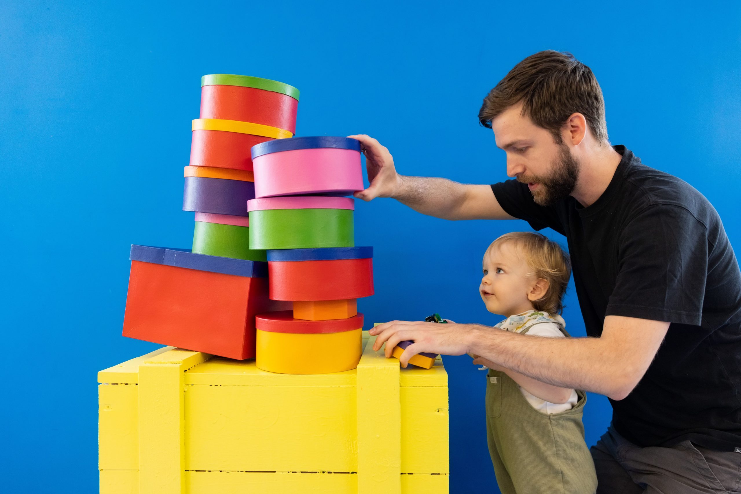 Father helps his young son stack multi-coloured building blocks as part of the Post and Play activities