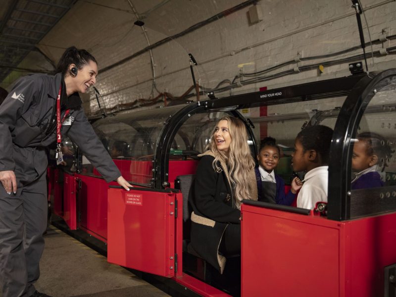 Member of the Visitor Experience team helping passengers board the red Mail Rail train