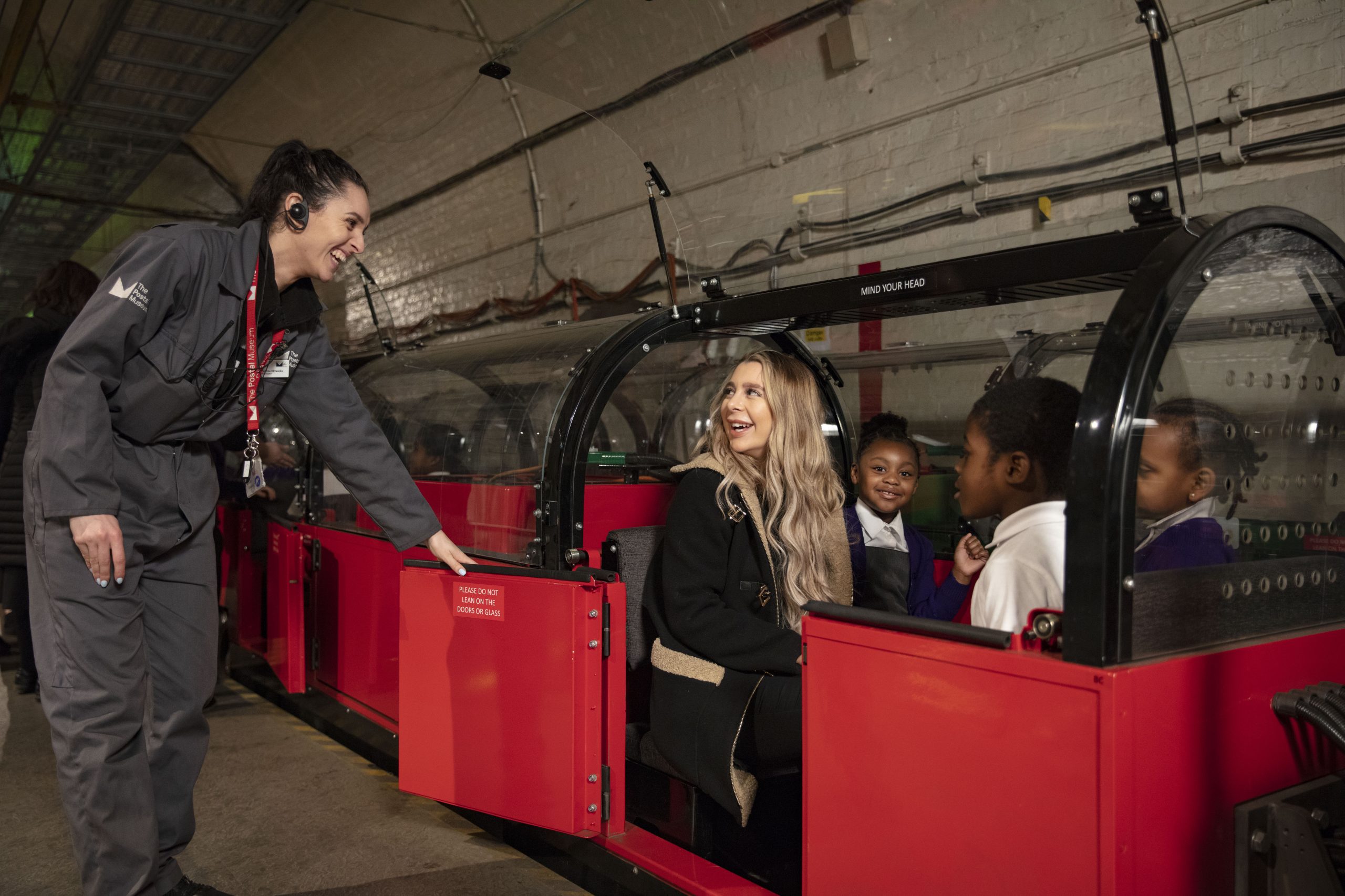 Member of the Visitor Experience team helping passengers board the red Mail Rail train