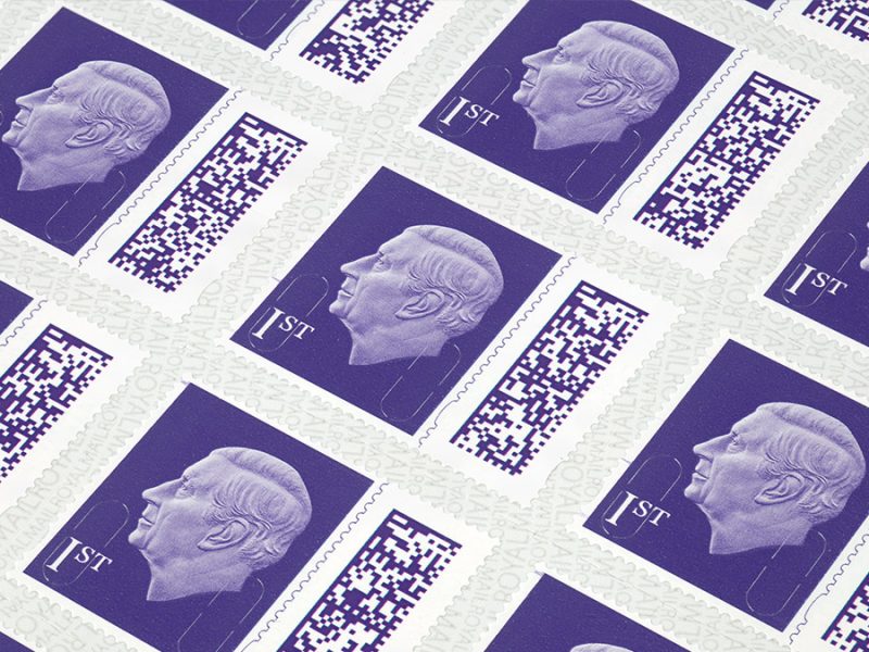 A closeup view of a sheet of purple stamps, showing a side profile of King Charles.