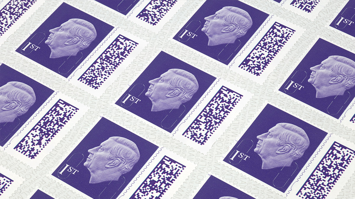 Purple 1st stamp of King Charles. A new addition is the barcode, which sits to the right of the main stamp. King Charles head, with no crown, sits in the middle of the stamp. 