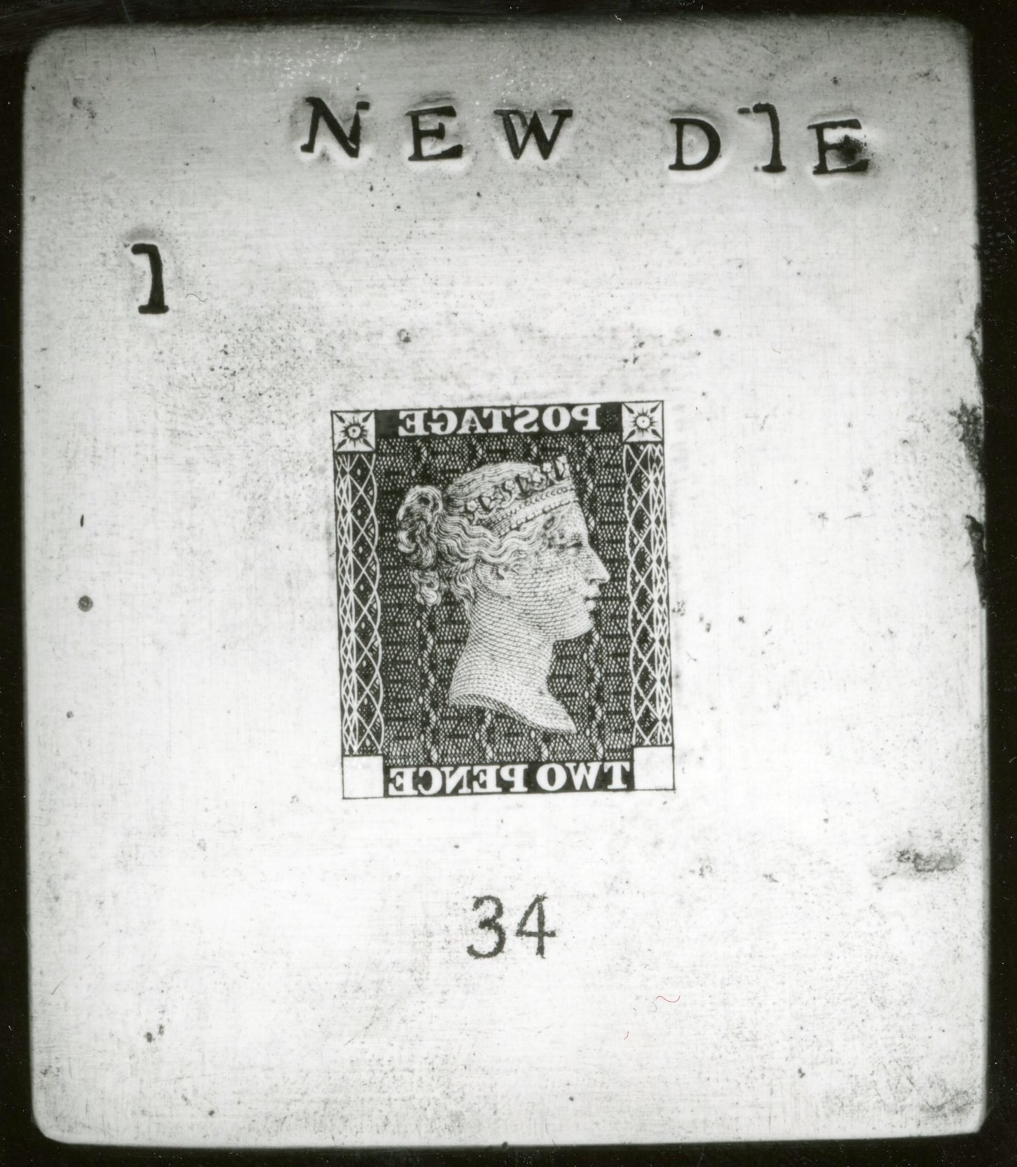 A metal die showing a stamp design in reverse, with a flipped portrait of Queen Victoria and the words 'Postage Two Pence' in reverse.