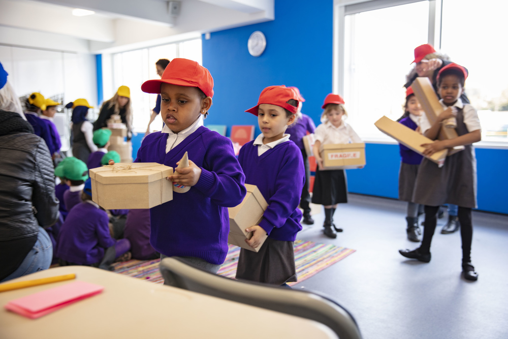 School aged children carry boxes and parcels to assemble in an interactive building game