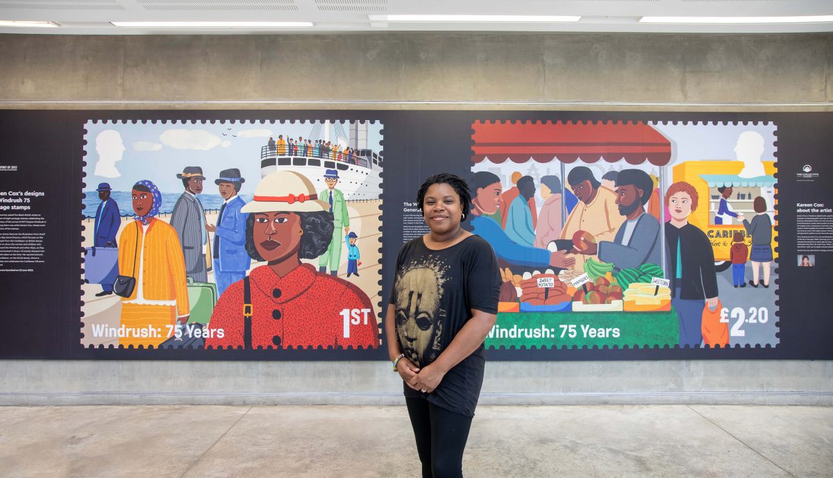 Black British artist Kareen Cox stands in front of enlarged images if her two stamps. The stamps are bright and colourful. One depicts Men, Women and Children departing from the HMT Empire Windrush, and the other shows people selling and buying food at a market stall. 