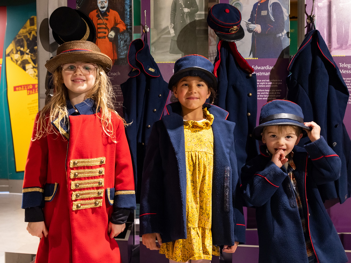 Photo of three children dressing up in postal uniforms.