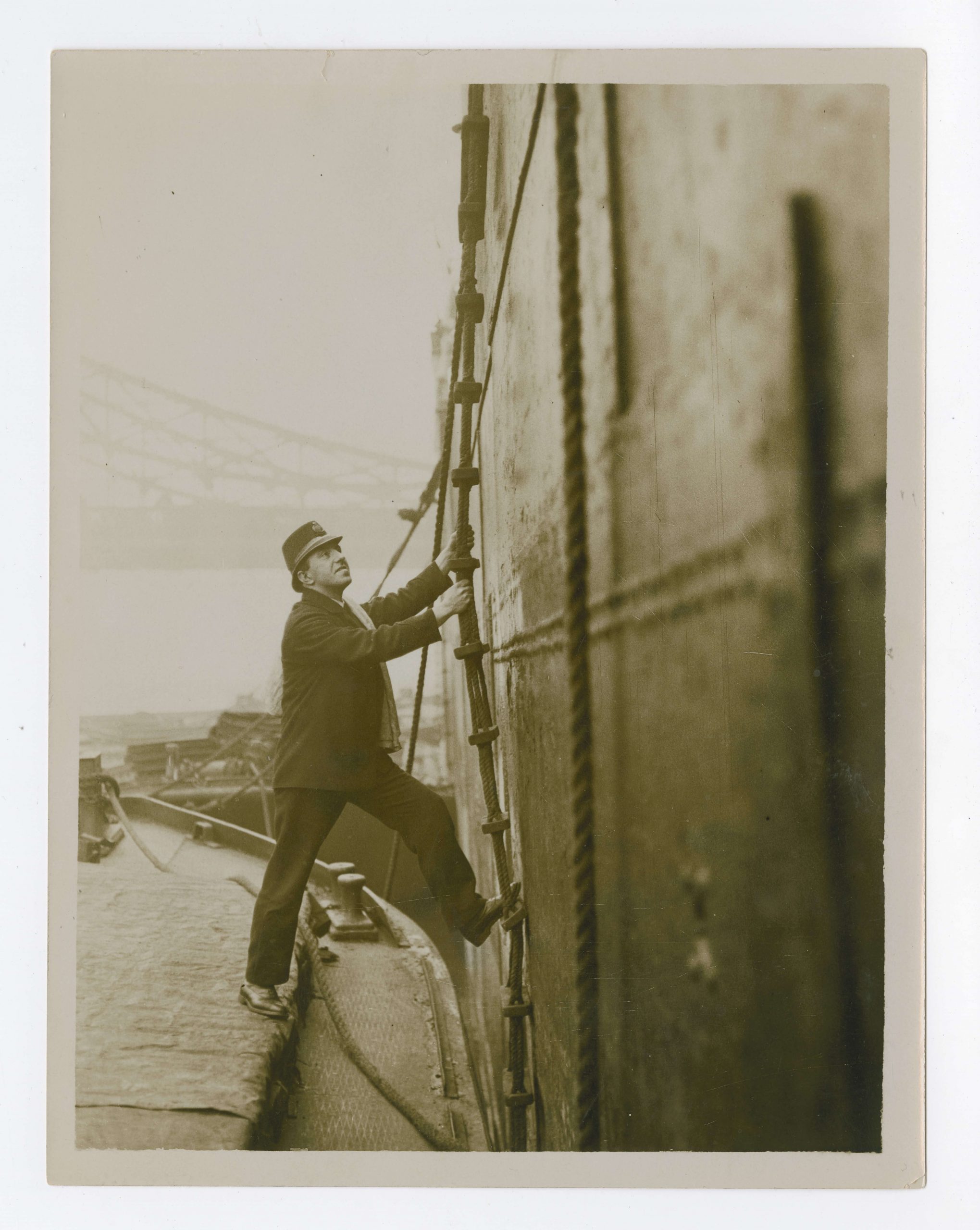 Herbet climbs up a rickety rope ladder, hanging off the side of a large ship. The ladder isn't fixed at the bottom of the boat, so climbing up and down would require a lot of core strength!