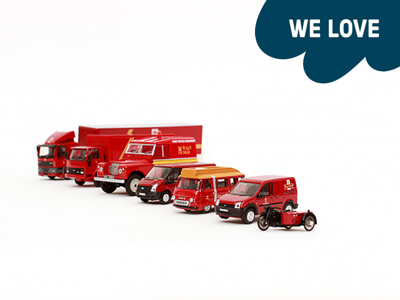 Red miniature toy vans, cars and a motorbike, lined up in a row.