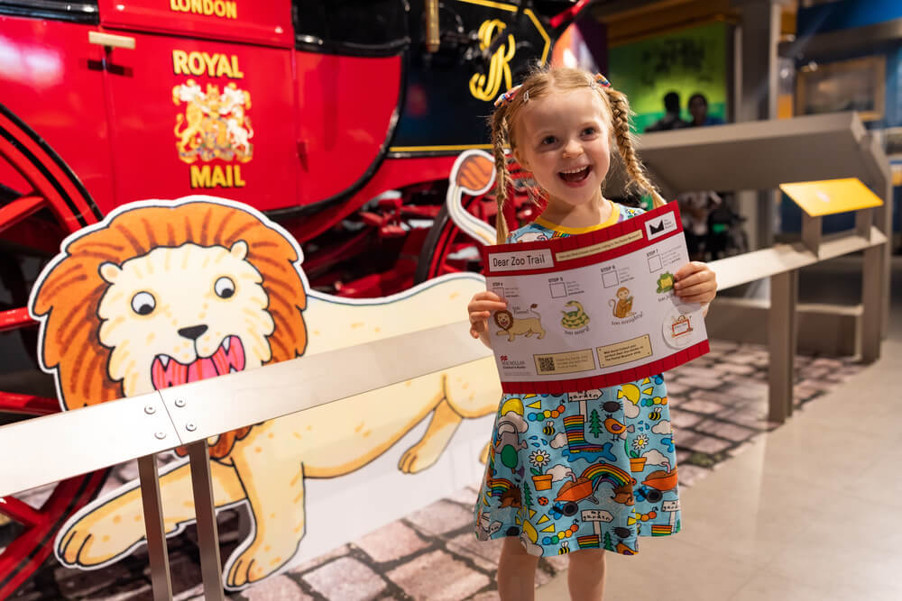 Small white girl holding a Dear Zoo exhibition trail map