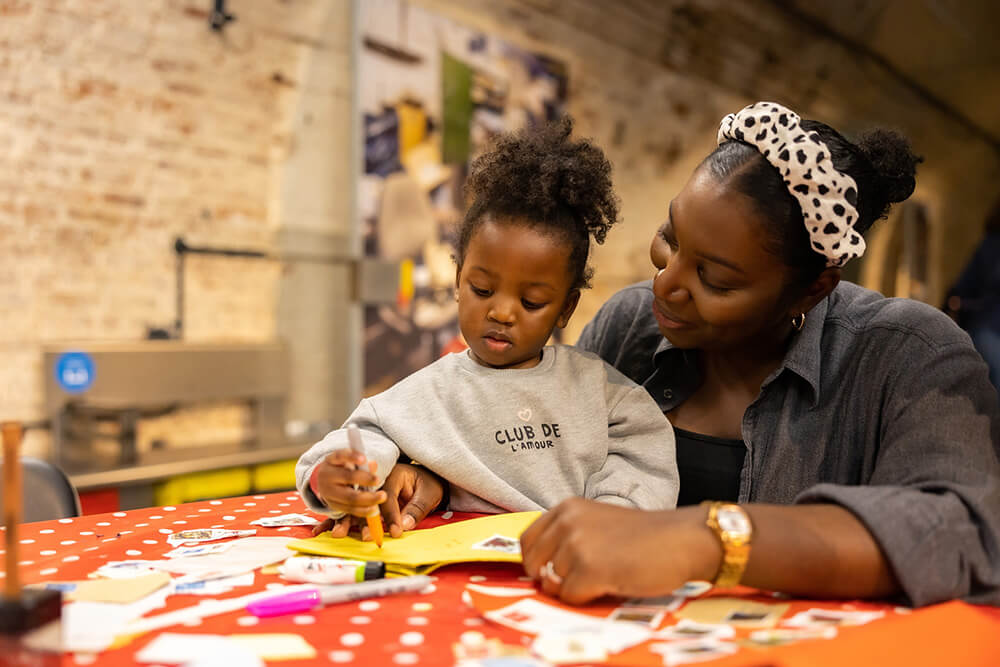 A mother and daughter doing arts and crafts activities around a table.