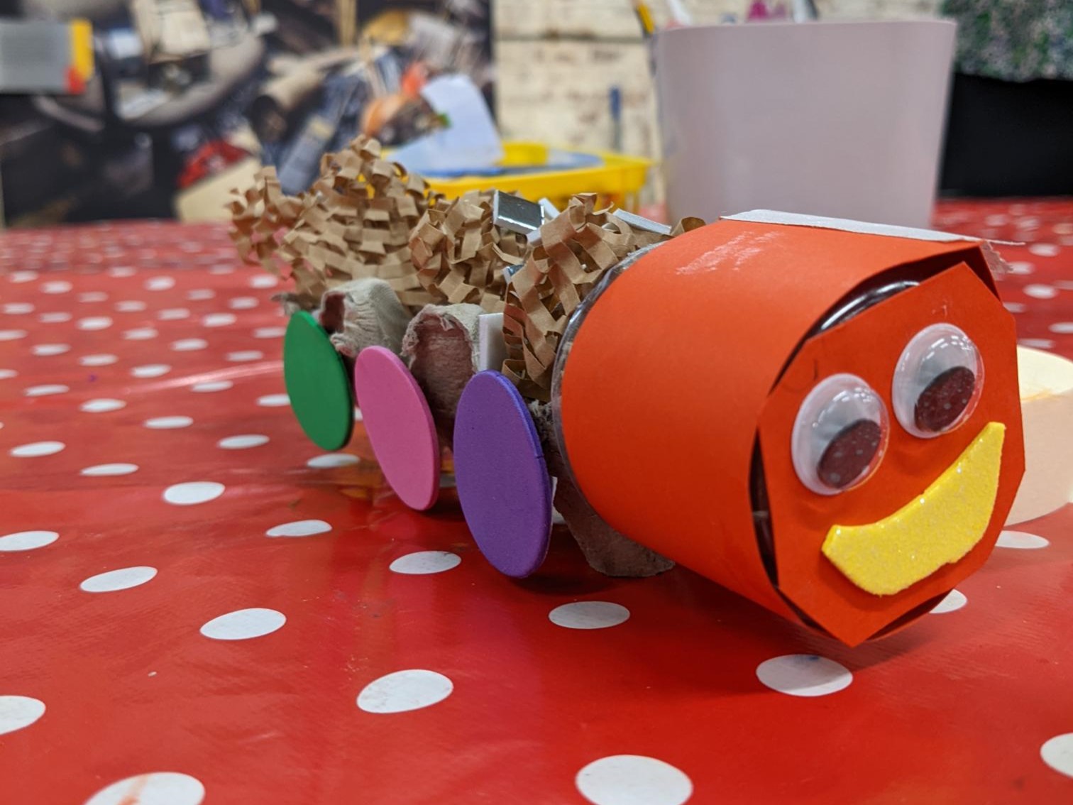 A carboard train made out of a red cylinder at the front and an egg tray as carriage. The train has carboard wheels and eyes and a big smile!