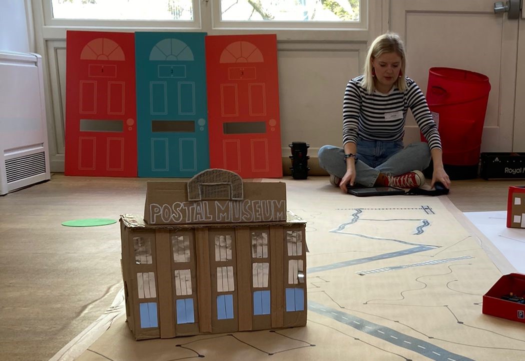 A carboard model of the museum's building, with big letters at the top of it reading Postal Museum.