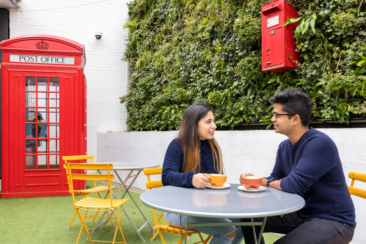 Two people drink coffee will chatting at The Postal Museum cafe