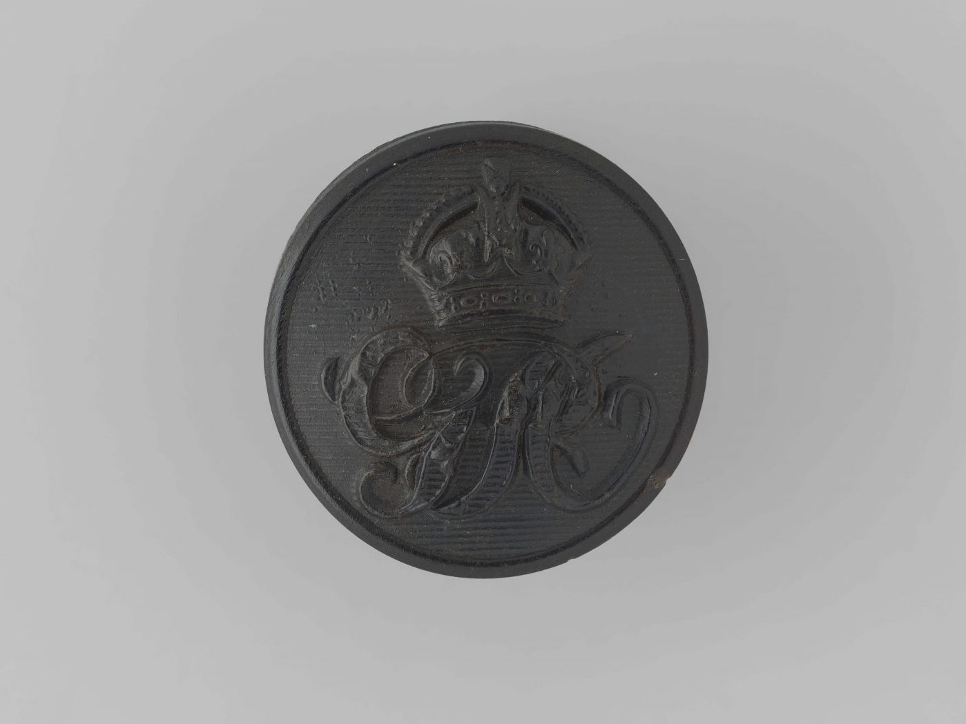 Black bottom with calligraphic overlapping letters G and R (George Rex) and the Tudor Crown