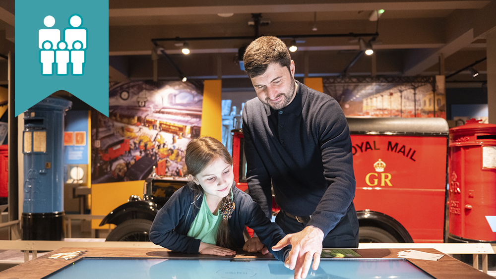 A parent and child exploring the touch table in The Postal Museum exhibition space.